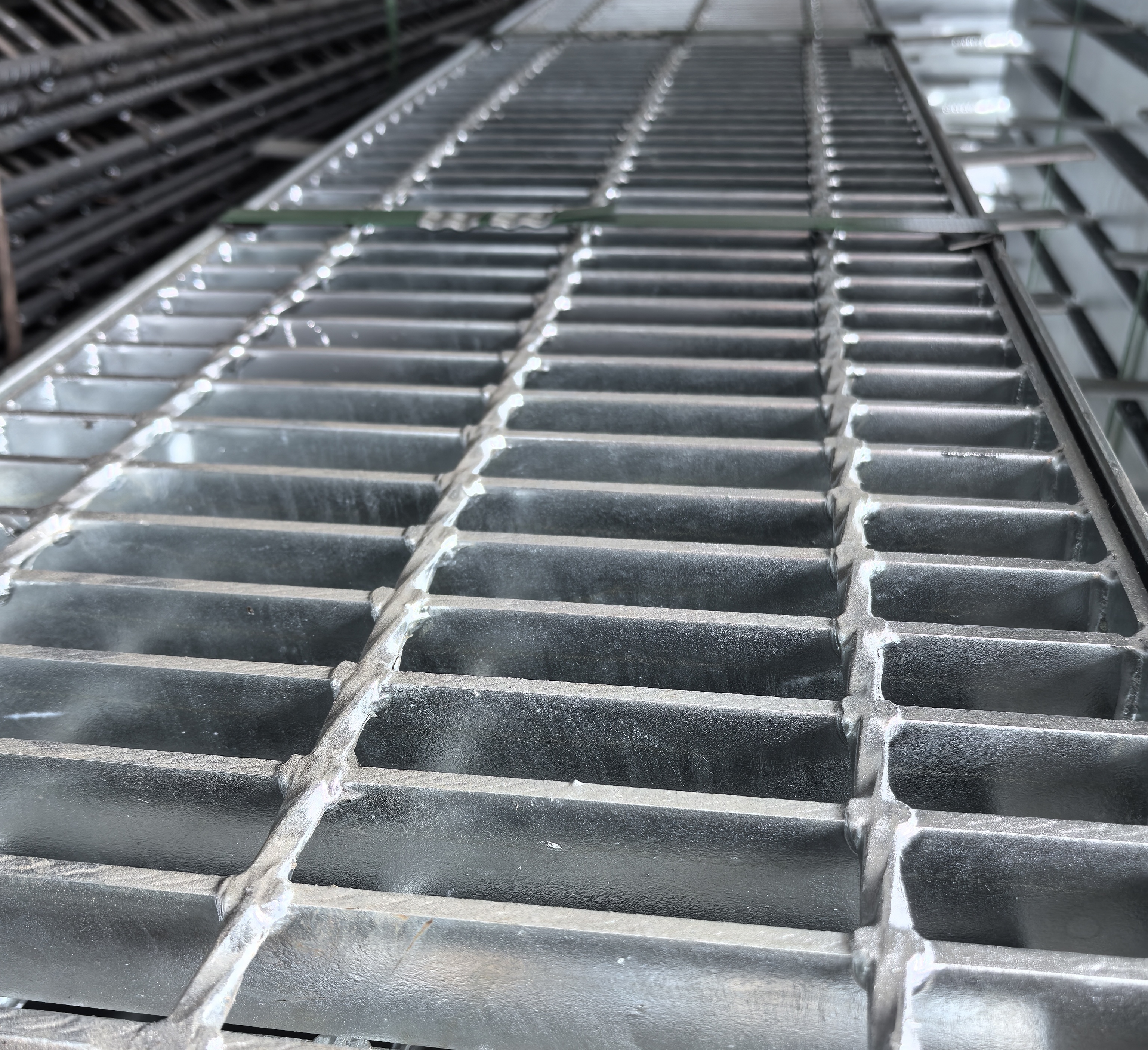 Close-up of industrial steel floor grating showing grid pattern and bearing bar construction